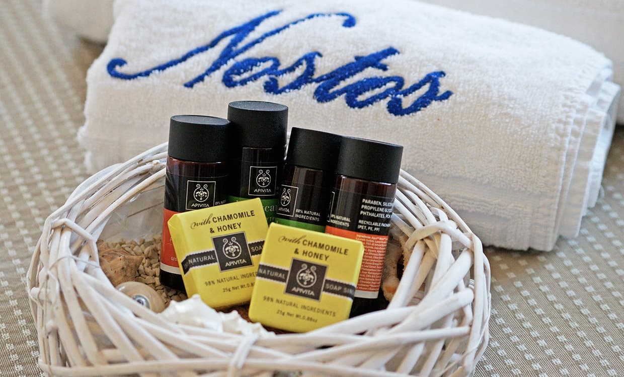 A basket of Apivita toiletries on an embroidered Nostos towel
